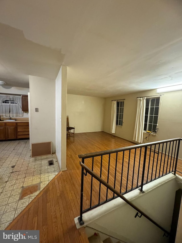 corridor featuring an upstairs landing, visible vents, light wood-style flooring, and a sink