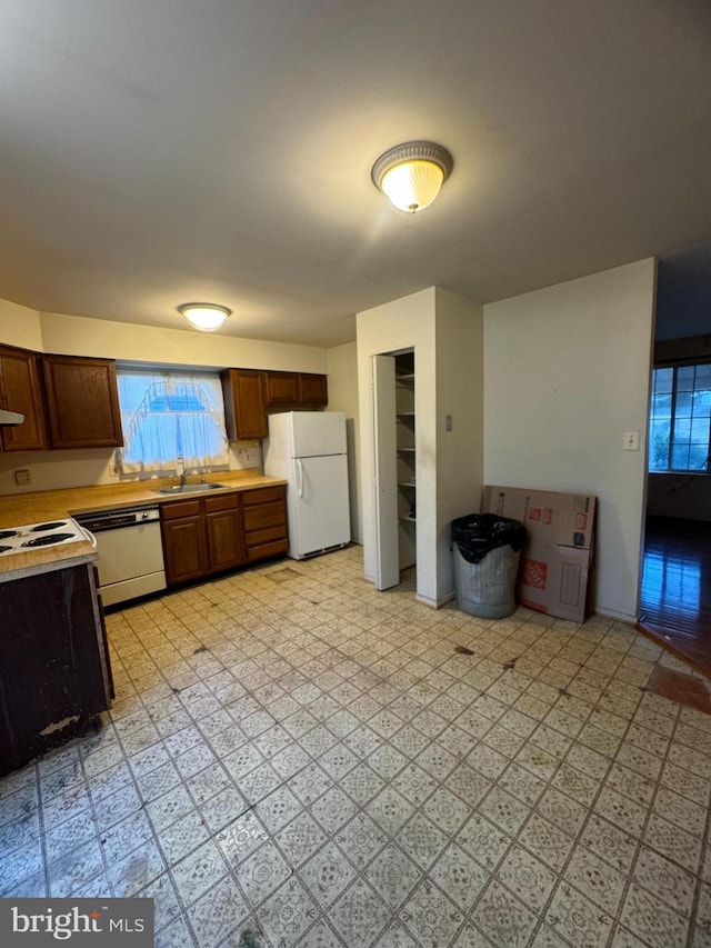 kitchen featuring light floors, white appliances, light countertops, and a sink