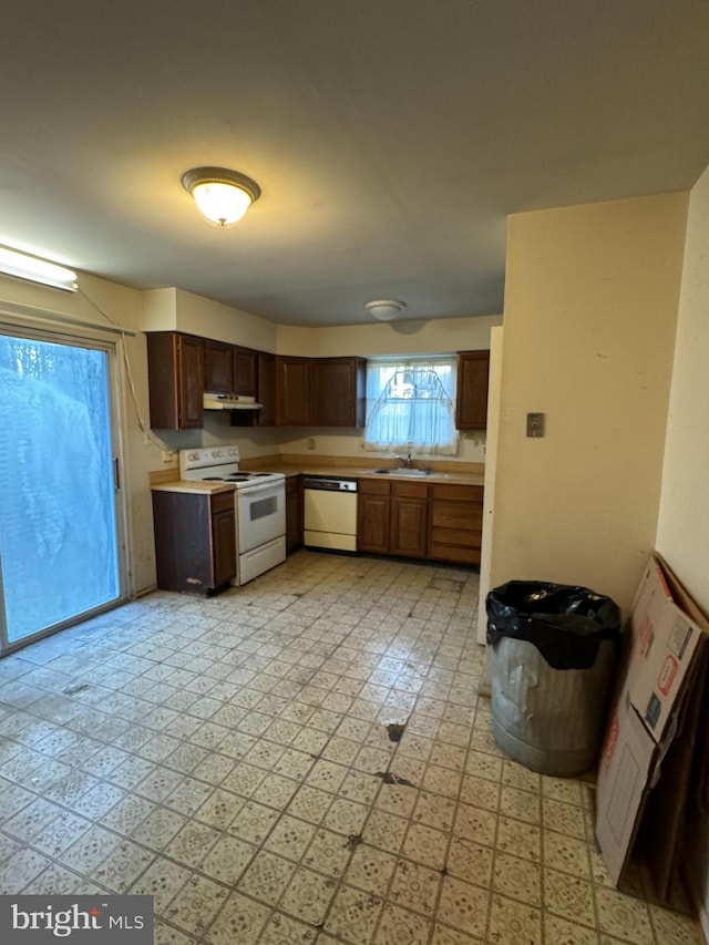 kitchen with under cabinet range hood, light floors, light countertops, white appliances, and a sink