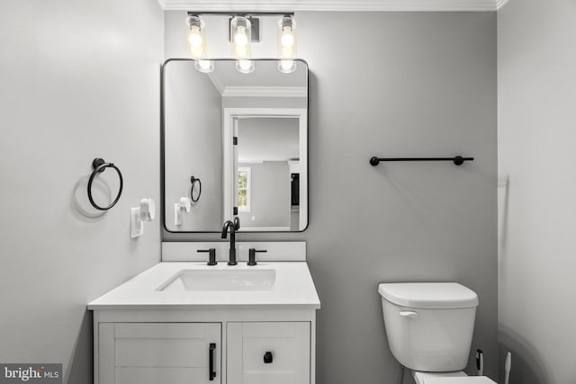 half bath with vanity, crown molding, and toilet