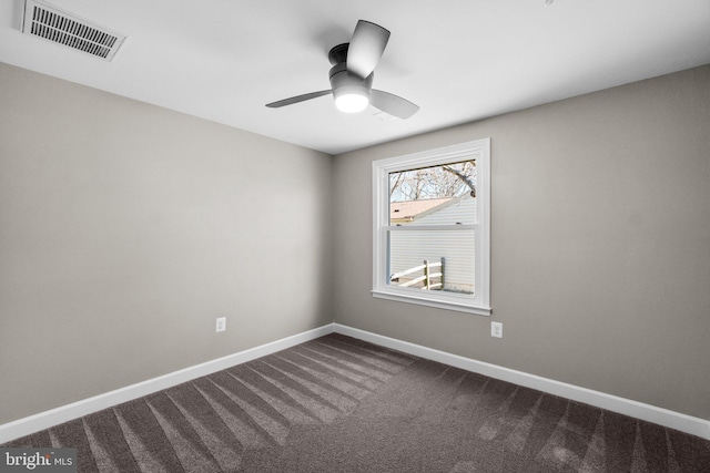 spare room featuring visible vents, a ceiling fan, baseboards, and dark colored carpet