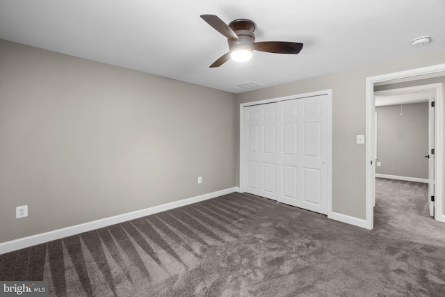 unfurnished bedroom with attic access, baseboards, a closet, and dark carpet