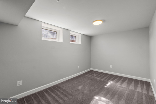 basement featuring dark colored carpet and baseboards