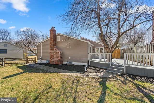 rear view of house with a yard, a fenced backyard, a wooden deck, and a chimney