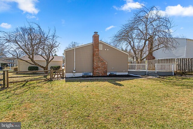 rear view of house featuring a lawn, a chimney, a deck, and fence