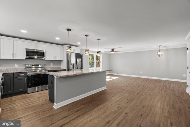 kitchen with a kitchen island, wood finished floors, white cabinetry, stainless steel appliances, and ceiling fan