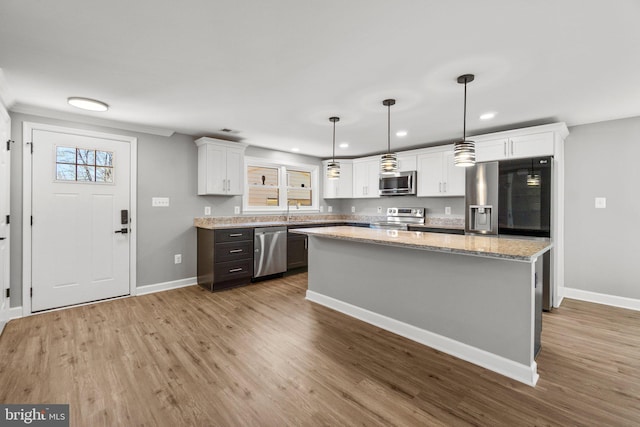 kitchen featuring a center island, appliances with stainless steel finishes, white cabinetry, and wood finished floors