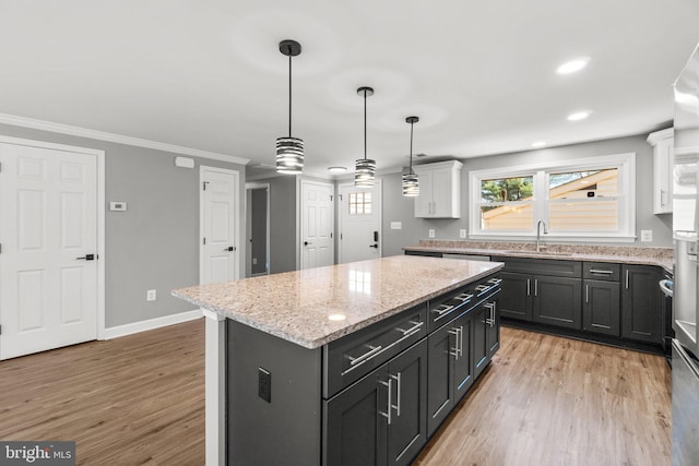 kitchen featuring a sink, white cabinetry, a kitchen island, and light wood finished floors