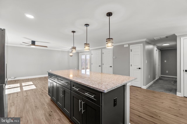 kitchen with light wood-type flooring, visible vents, ornamental molding, and a center island