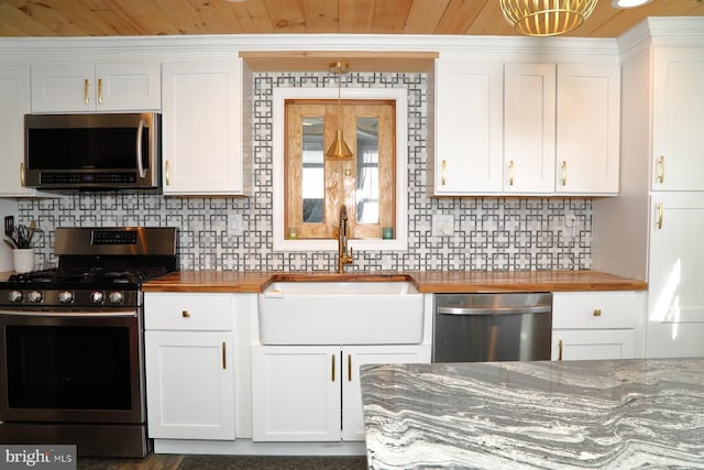 kitchen with a sink, stainless steel appliances, white cabinetry, tasteful backsplash, and butcher block counters