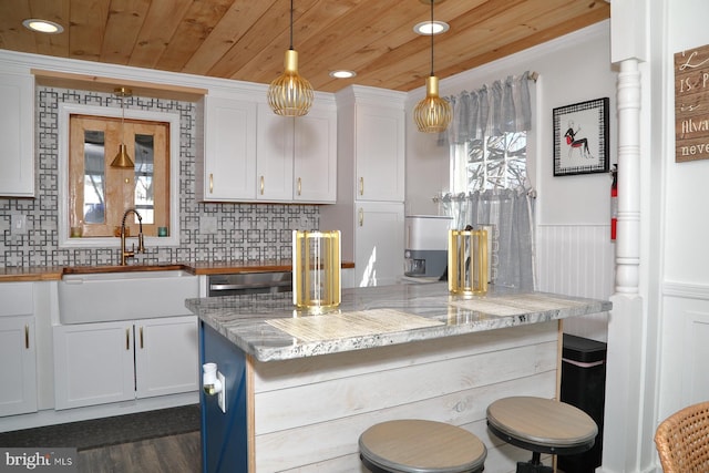 kitchen with a wainscoted wall, a sink, white cabinetry, wooden ceiling, and decorative backsplash