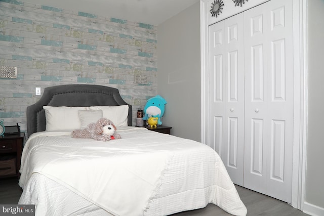 bedroom featuring a closet, wood finished floors, and an accent wall