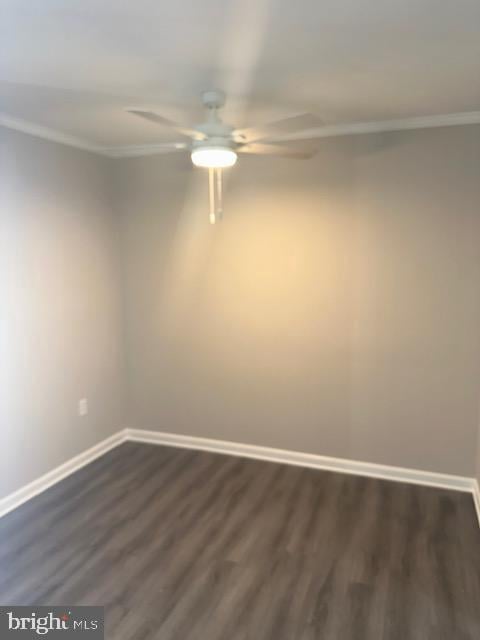 unfurnished room with crown molding, baseboards, dark wood-type flooring, and a ceiling fan