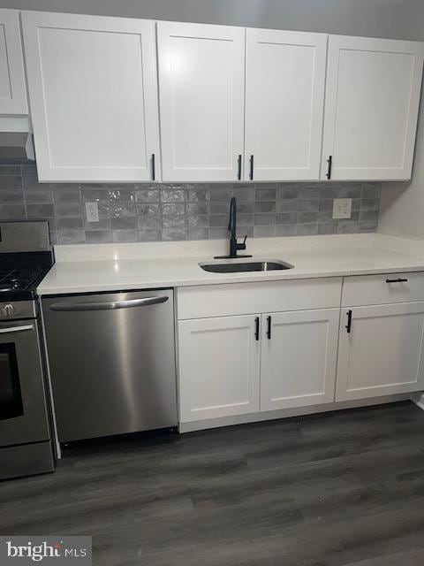 kitchen with a sink, stainless steel appliances, white cabinets, and dark wood-style flooring