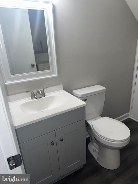 half bath with vanity, toilet, and wood finished floors