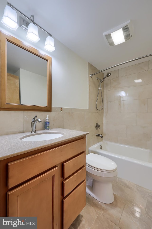 bathroom with visible vents, toilet, vanity, bathtub / shower combination, and tile walls