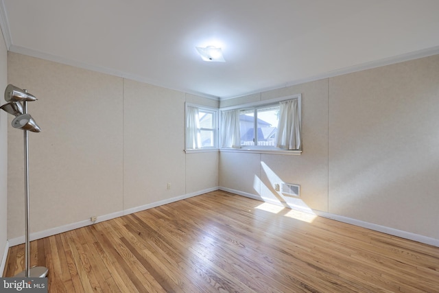 empty room featuring crown molding, wood finished floors, visible vents, and baseboards