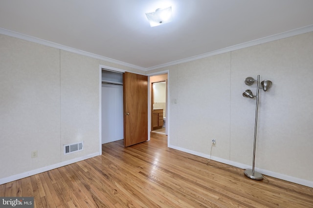 unfurnished bedroom with hardwood / wood-style flooring, crown molding, visible vents, and a closet