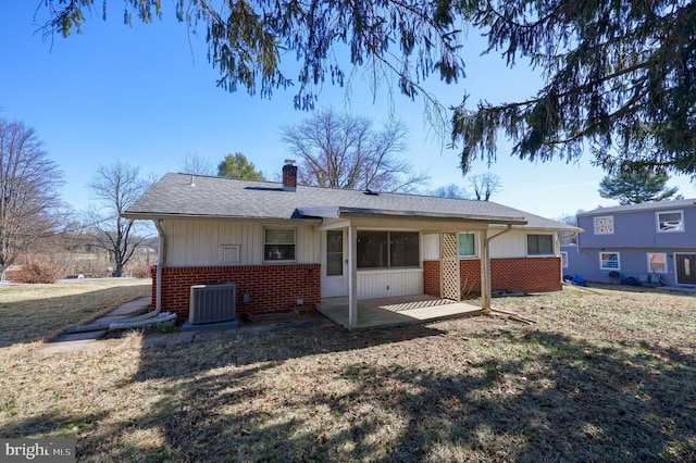 rear view of house with a patio, cooling unit, a chimney, a lawn, and brick siding