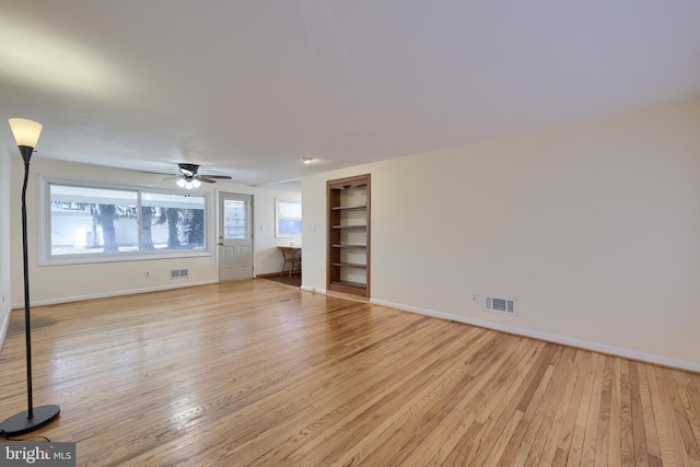 unfurnished living room featuring visible vents, light wood-type flooring, and built in features