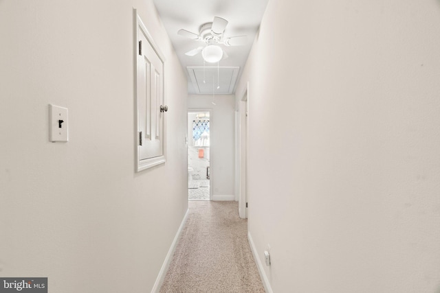 hall with baseboards, light carpet, and attic access