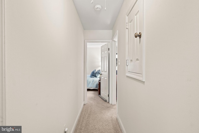 corridor featuring baseboards and light colored carpet