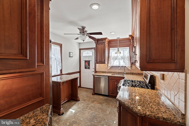 kitchen featuring a sink, light stone counters, a wealth of natural light, and stainless steel appliances