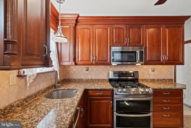 kitchen with pendant lighting, a sink, stone countertops, tasteful backsplash, and appliances with stainless steel finishes