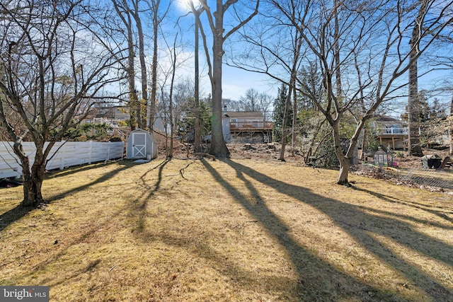 view of yard featuring a storage shed, fence, and an outdoor structure