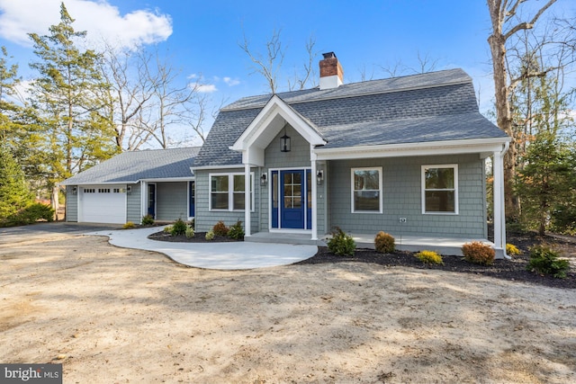 colonial inspired home featuring a garage, driveway, a chimney, and roof with shingles