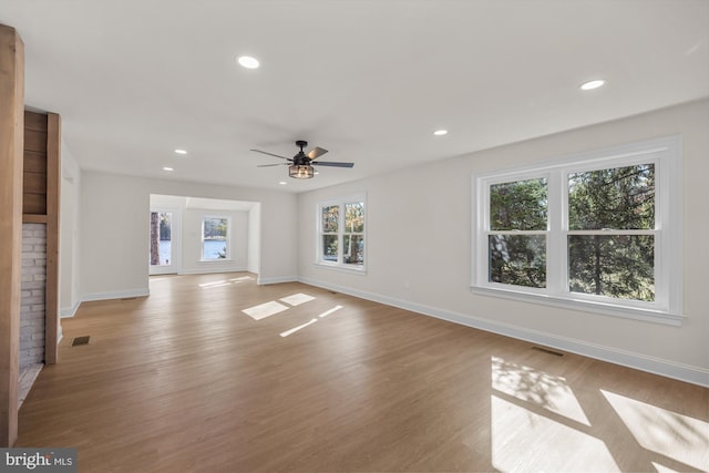 unfurnished living room featuring visible vents, light wood-type flooring, and baseboards