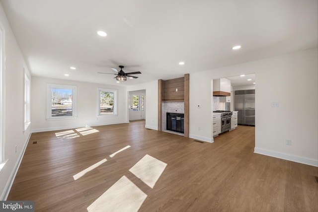 unfurnished living room with recessed lighting, light wood-type flooring, baseboards, and a fireplace