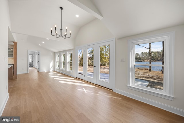 interior space with lofted ceiling with beams, light wood-type flooring, baseboards, and a notable chandelier