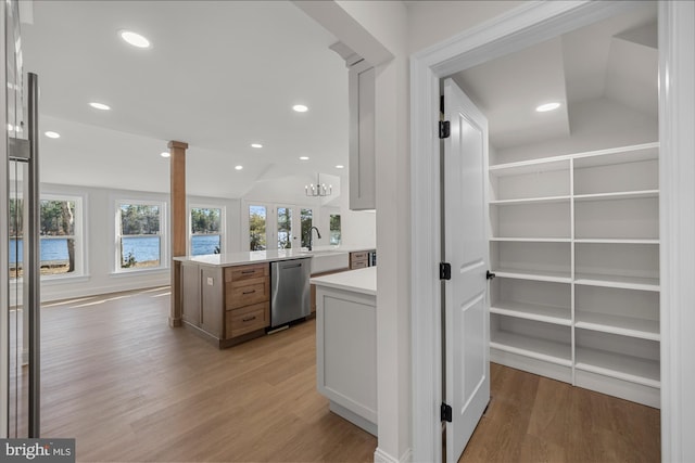 interior space with a wealth of natural light, dishwasher, light wood-style flooring, and a sink