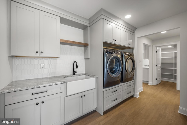 clothes washing area with recessed lighting, separate washer and dryer, wood finished floors, cabinet space, and a sink