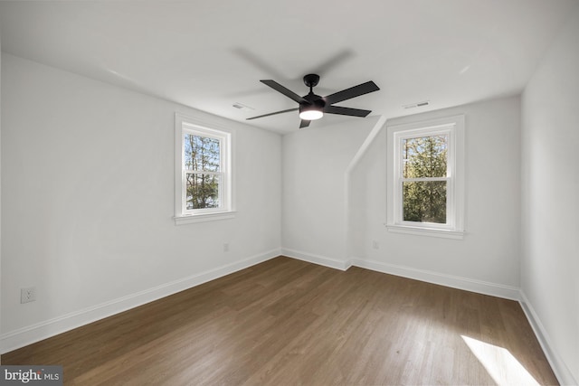 spare room featuring dark wood finished floors, plenty of natural light, baseboards, and visible vents