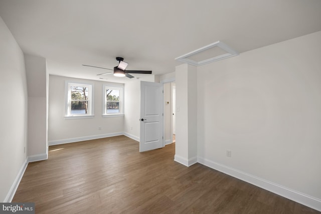 unfurnished bedroom with baseboards, attic access, ceiling fan, and dark wood-style flooring