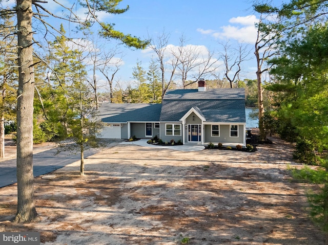 colonial inspired home with a garage and dirt driveway