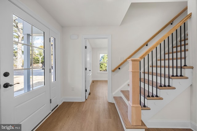 entryway with stairs, wood finished floors, and baseboards