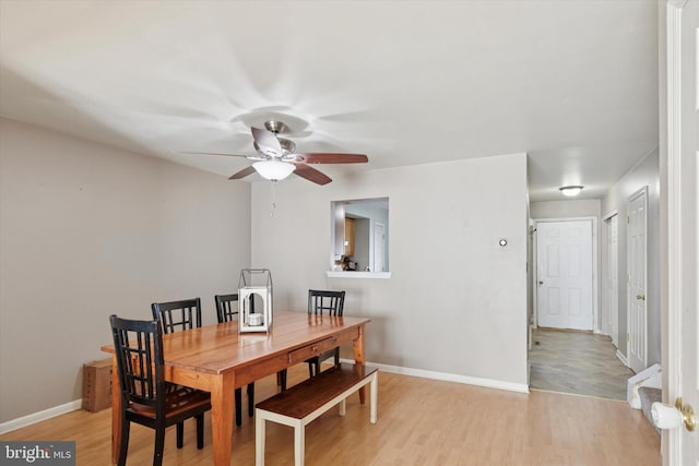 dining space with a ceiling fan, baseboards, and light wood finished floors