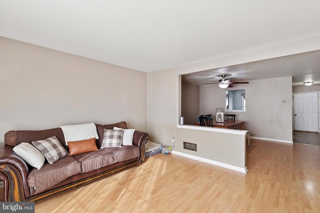 living room featuring a ceiling fan, wood finished floors, and baseboards