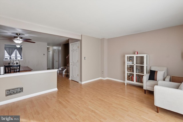 sitting room with light wood-type flooring, baseboards, visible vents, and a ceiling fan