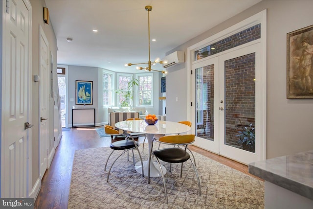 dining space featuring a chandelier, wood finished floors, recessed lighting, french doors, and an AC wall unit