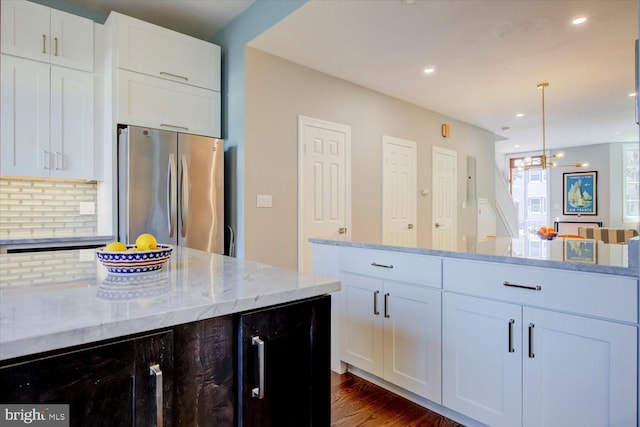 kitchen with light stone counters, wine cooler, backsplash, freestanding refrigerator, and dark wood finished floors