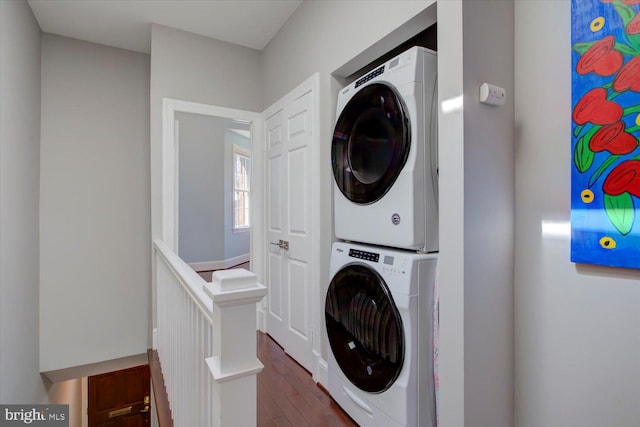clothes washing area with laundry area, stacked washer / dryer, and dark wood-type flooring