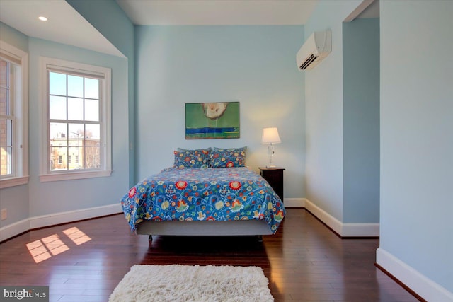 bedroom featuring hardwood / wood-style flooring, baseboards, a wall mounted air conditioner, and recessed lighting