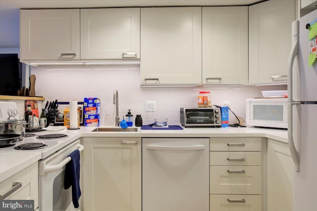 kitchen with light countertops, tasteful backsplash, white appliances, a toaster, and a sink