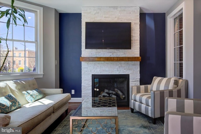 living room with a stone fireplace and baseboards