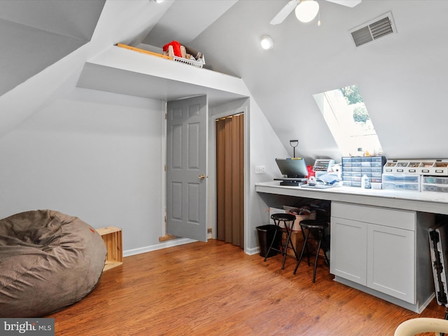 office area featuring visible vents, baseboards, vaulted ceiling with skylight, ceiling fan, and light wood-style floors