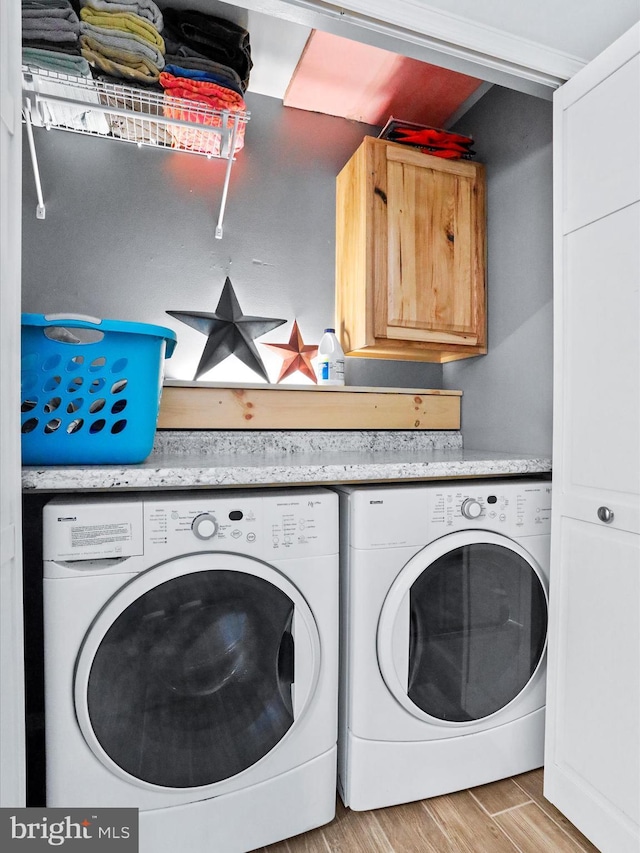 laundry room featuring cabinet space, separate washer and dryer, and light wood-style floors